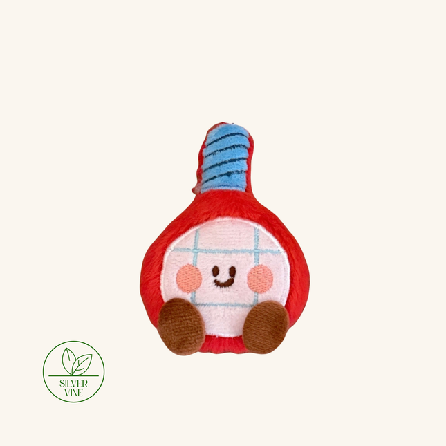 A plush toy shaped like a red and white pepper with a blue striped top, featuring a smiling face and brown feet, shown on a light beige background with a Silver Vine logo in the bottom-left corner.