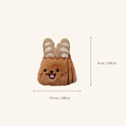 A small plush bunny-shaped accessory centered on a light beige background, with measurement arrows and text showing dimensions of 7.5 cm by 9 cm.