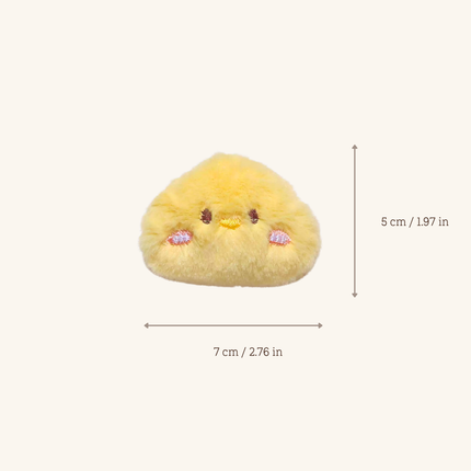 A small yellow plush character toy centered on a light beige background, with measurement arrows and text showing dimensions of 7 cm wide by 5 cm high.