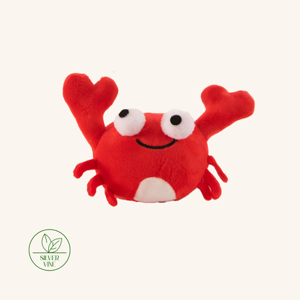 A red plush crab toy with large white eyes, a black stitched smile, and small black legs, centered on a light cream background. A green 'Silver Vine' logo appears in the lower-left corner.