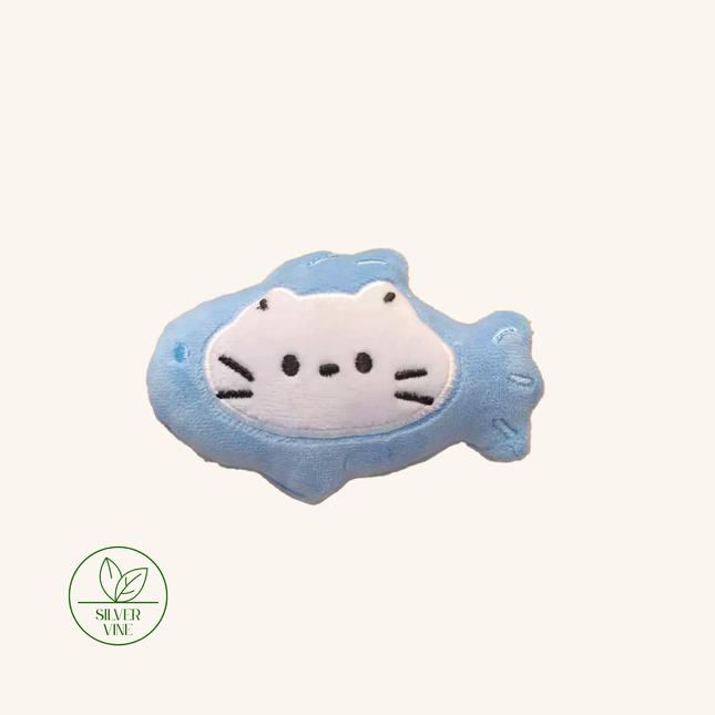A light blue plush fish-shaped hair clip with a white cat face design, shown on a solid off-white background with a 'Silver Vine' brand logo in the bottom-left corner.