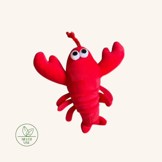 A red plush lobster toy with large white eyes and raised claws, shown on a plain light beige background. A green 'Silver Vine' logo appears in the lower-left corner.