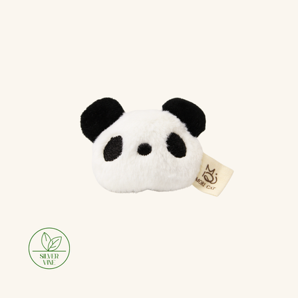 A plush panda head hair accessory in black and white faux fur, featuring a small beige fabric tag with a cat logo and a green 'Silver Vine' brand seal in the lower-left corner, set against a solid cream background.