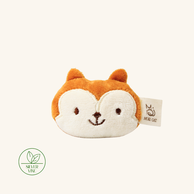 A plush fox face coin purse in orange and cream, featuring embroidered eyes, nose, and mouth, with a 'MINI CAT' brand tag on the side. A green 'SILVER VINE' logo is visible in the bottom-left corner against a solid cream background.