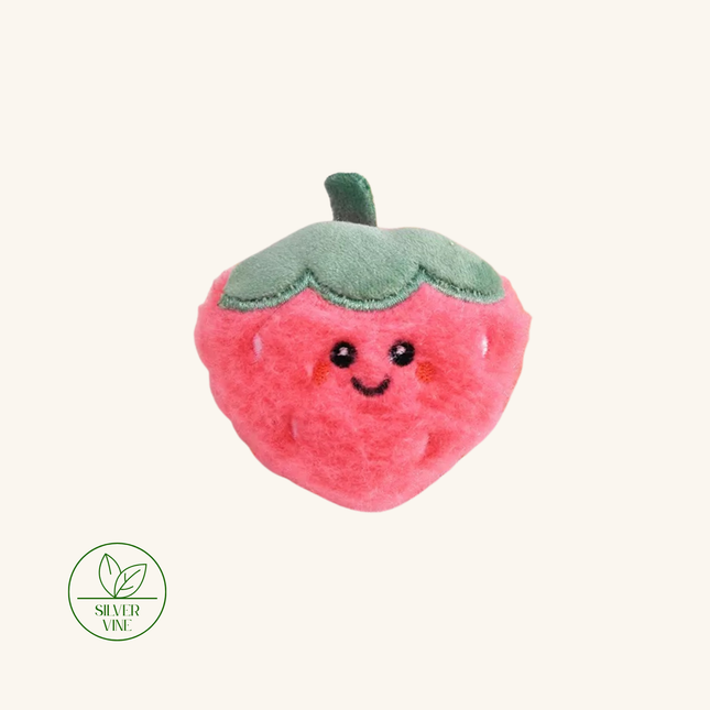A cute, plush strawberry-shaped accessory with a smiling face, featuring a pink body and a green top, shown on a light cream background with a Silver Vine logo in the bottom-left corner.